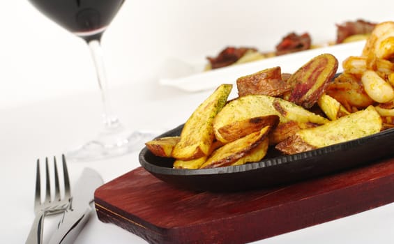 Main Dish: Fried Potato Slices with cutlery and glass of red wine (Selective Focus)