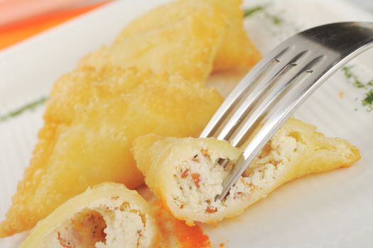 Appetizer: Empanada de Queso de Cabra (Pasty filled with goat cheese) cut in half with fork (Selective Focus)