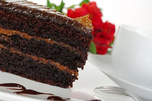 Chocolate cake with coffee and a red Inca Lily in the background (Selective Focus)