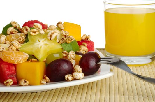 Tropical fruit salad with puffed wheat cereal on table mat with orange juice in the background (Selective Focus, Isolated)  