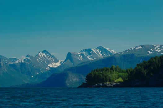 The Romsdalsfjorden close to Andalsnes in Norway in summer with green trees and snow on the top of the mountains