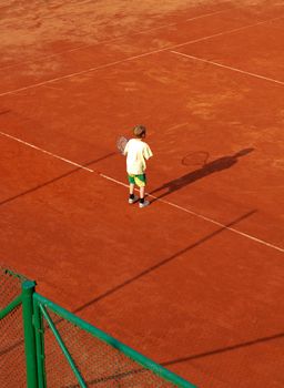 boy on ground tennis court awaiting the opponent