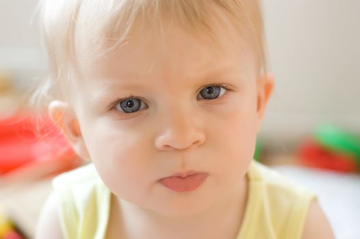 Serious baby girl face over colorful back, soft focus