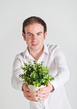 Happy young man holds a pot with decoration plant