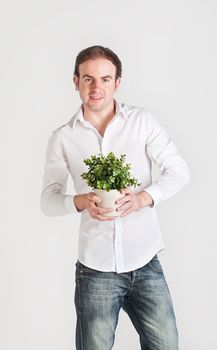 Happy young man holds a pot with decoration plant