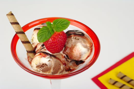 Chocolate and vanilla ice-cream scoops with strawberry, mint leaf, waffle roll, strawberry and chocolate syrup (Selective Focus)