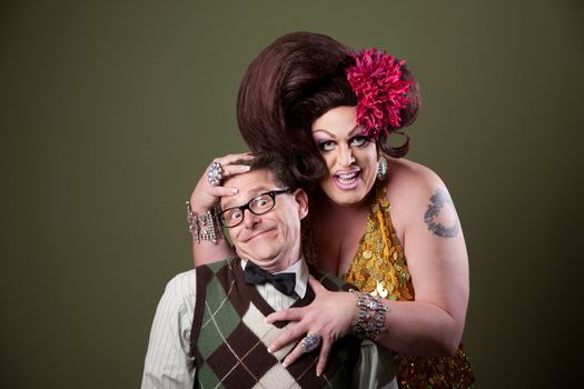 Drag queen holds a Caucasian nerd on green background 