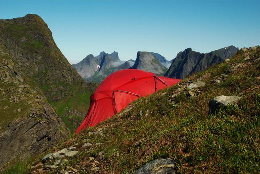 Red tent set up on a steep hillside on Moskenesoya, Lofoten, Norway 