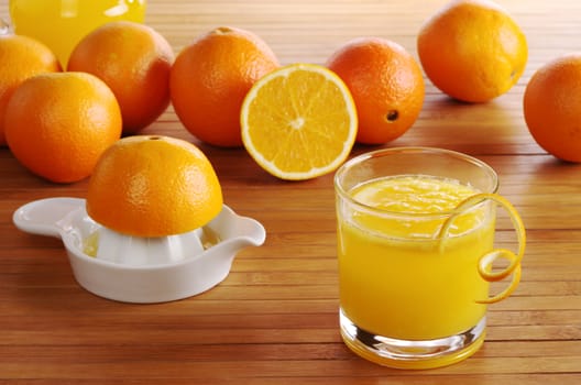 Fresh orange juice with orange juice squeezer and oranges on wooden mat (Selective Focus)