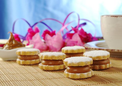 Peruvian cookies called Alfajor on tablemat with coffee and pink flowers in the background (Selective Focus)