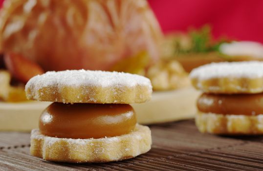 A Peruvian cookie called alfajor filled with manjar (a cream similar to caramel) on table mat with a baked apple in the background (Selective Focus)