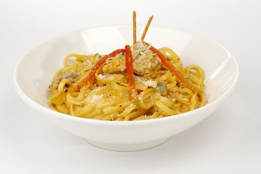 Fettuccine with chicken, mushrooms and red pepper garnished with sticks on white (Selective Focus) 