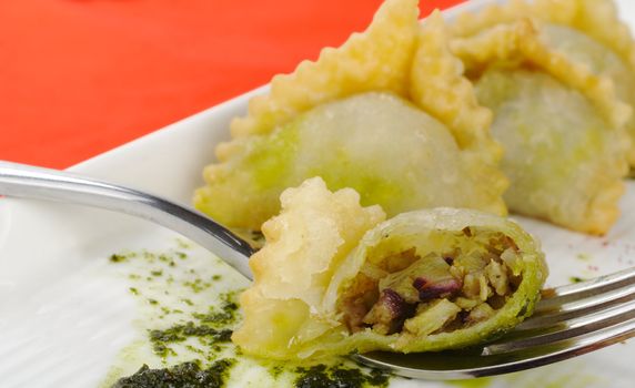 Appetizer: Empanada filled with meat cut in half on fork (Selective Focus)