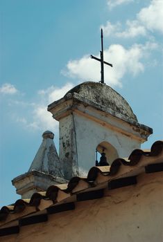 A steeple with a cross on top and two bells in Medellin, Colombia