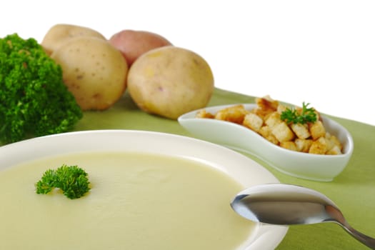 Potato soup with parsley on top and ingredients in the background isolated on white (Selective Focus)