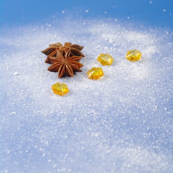 Star anise with yellow stones on blue background covered by icing sugar (Selective Focus) 