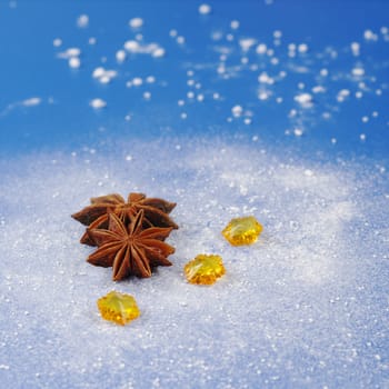 Star anise with yellow stones on blue background covered by icing sugar looking like snow (Selective Focus) 