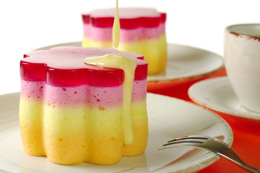 Pouring vanilla sauce over the Peruvian colorful small cake called Torta Helada in the shape of a flower (Selective Focus) 