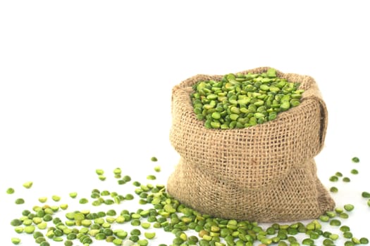 Split dried green peas in jute sack on white (Selective Focus, Focus on the peas in the front in the sack)