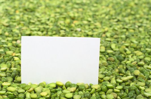 Split dried green peas with a blank card (Selective Focus, Focus on the card)