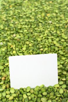 Split dried green peas with a blank card (Selective Focus, Focus on the card)