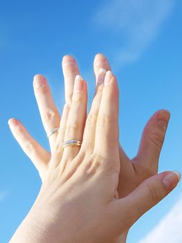 Married couple holding hands towards fresh blue sky