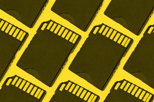 Close up on a pattern of black SD memory cards arranged with yellow filter