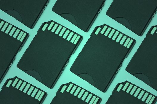 Close up on a pattern of black SD memory cards arranged with green filter