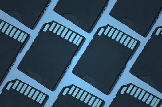 Close up on a pattern of black SD memory cards arranged with blue filter