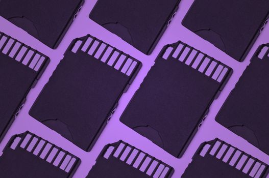 Close up on a pattern of black SD memory cards with purple filter