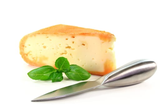 a piece of soft cheese with basil on a white background