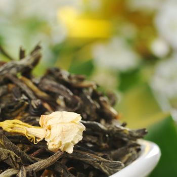 Loose green tea with jasmine flowers with some white flowers in the background (Selective Focus, Focus on the jasmine flower) 