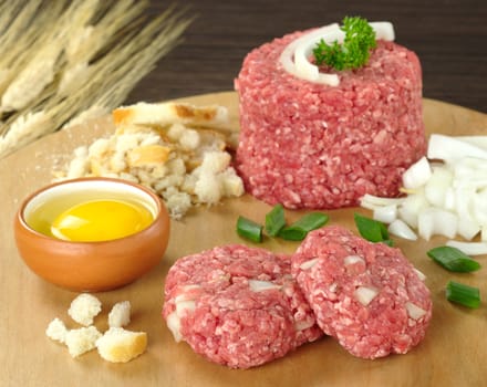 Preparing meatball with ingredients, such as egg, ground meat, dried bread, onions on wooden board (Selective Focus, Focus on raw meatballs)