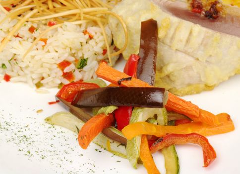 Fried vegetable slices: aubergine (eggplant), bell pepper, green squash (zucchini) with risotto and fish in batter in the background (Selective Focus, Focus on the front of the vegetables)