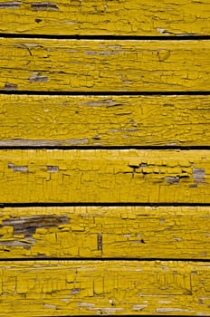 Ancient yellow painted wooden wall with peeling paint background.