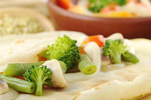 Broccoli, mushrooms, beans, onions and pepper on pancake (Selective Focus, Focus on the broccoli, bean and mushroom in the front as well as the edge of the pancake in the right bottom corner)