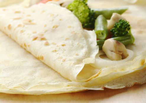 Thin pancakes filled with broccoli, onion, mushroom and beans (Selective Focus, Focus on the front edge of the pancakes)