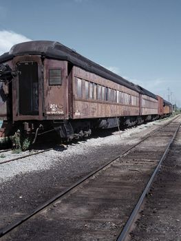 An old passenger train rotting away in a rail yard. 35mm film scan.
