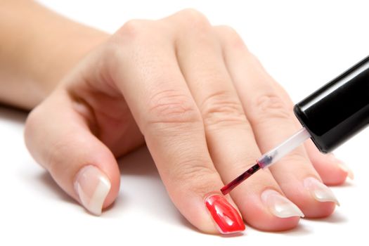 Woman painting her fingernails. White background.