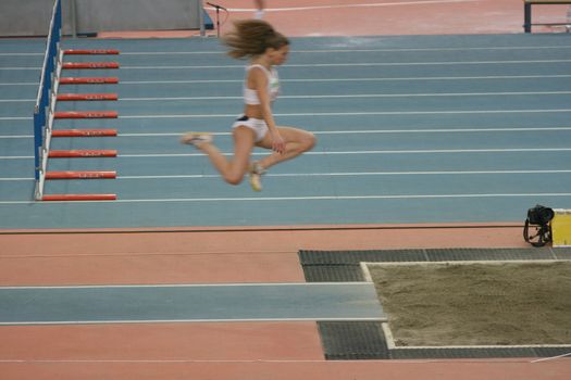 woman athlete performing triple long jump on races