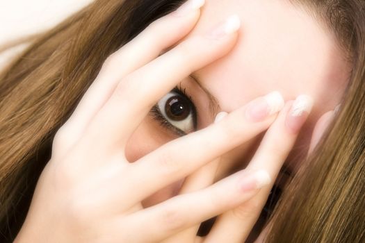 Studio portrait of pretty brunette looking through her fingers