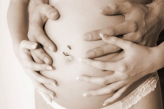 Portrait of 4 hands on a pregnant belly