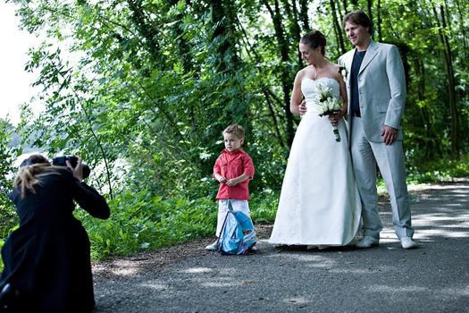 pictures being shot of a wedding couple and their son