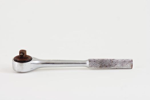 A well used socket wrench on a white background.