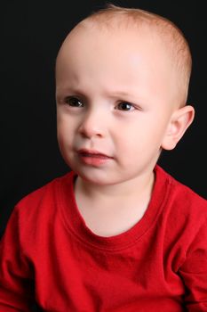 Cute toddler wearing a red shirt with a frown