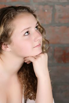 Beautiful teen with curly hair against a brick wall background 