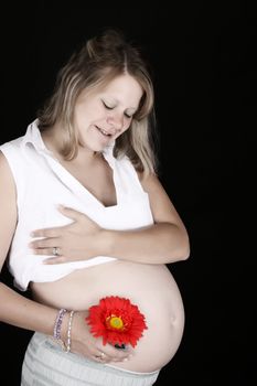 Heavily pregnant blond female against a black background