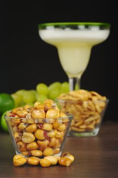 Canchas: Peruvian roasted corn eaten as snack with the cocktail called Pisco Sour in the back with limes and grapes (Selective Focus, Focus on the front) 