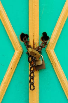 Green and yellow door with chain and three locks 