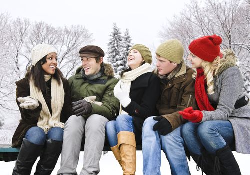 Group of young friends talking and laughing outdoors in winter